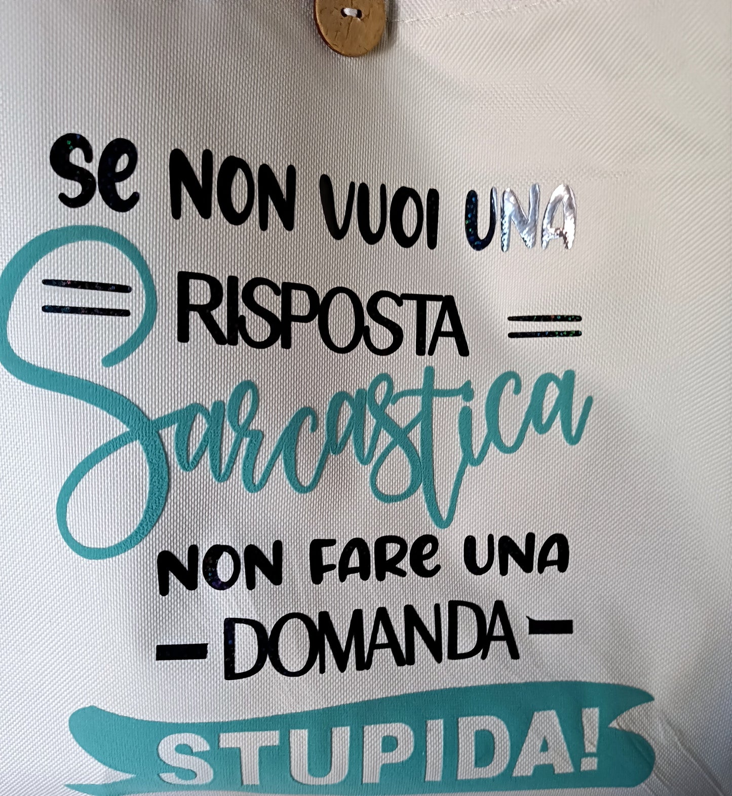 Italian sarcastic quote printed on a white fabric bag with black and teal lettering