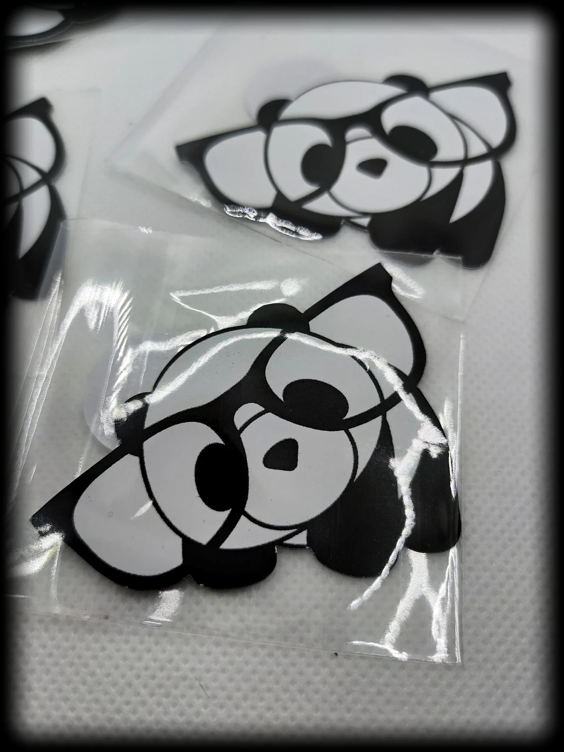 Black and white cartoon panda stickers on textured white surface in plastic sleeves