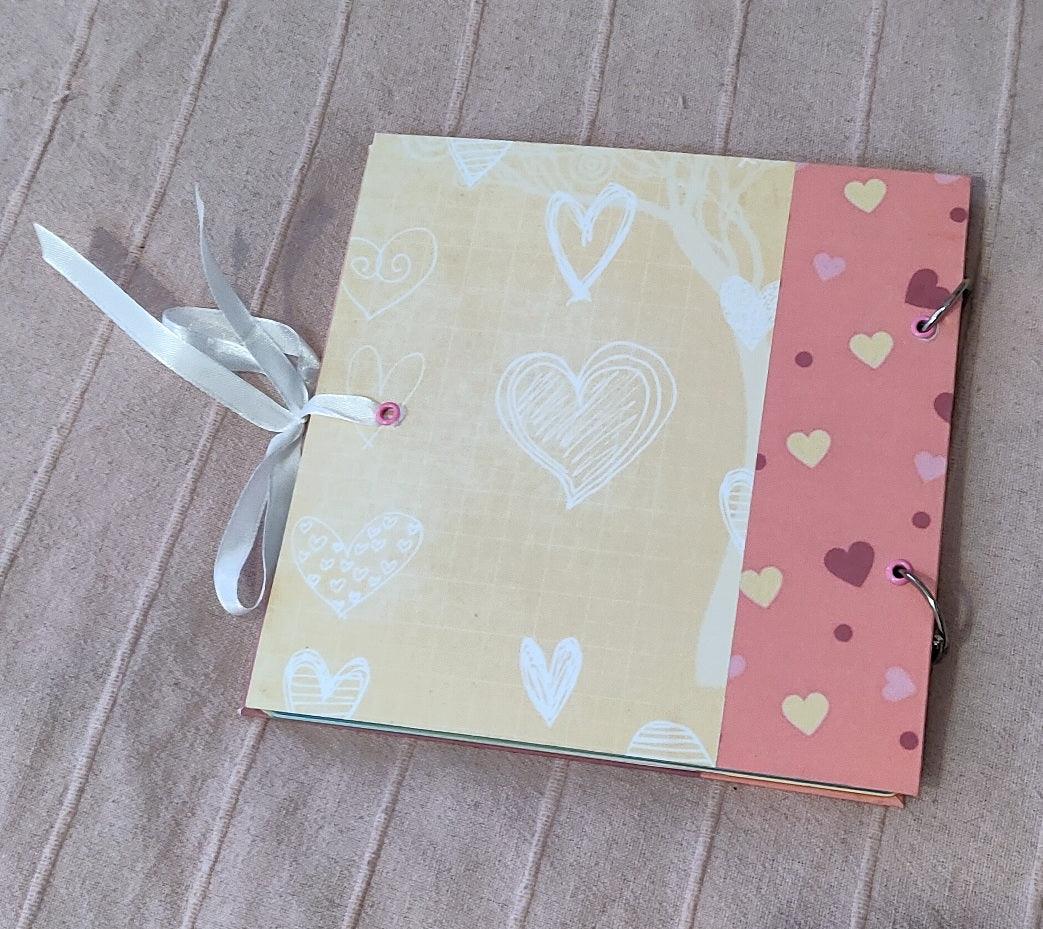 Handmade scrapbook album with heart patterns, pink and beige cover, ribbon closure