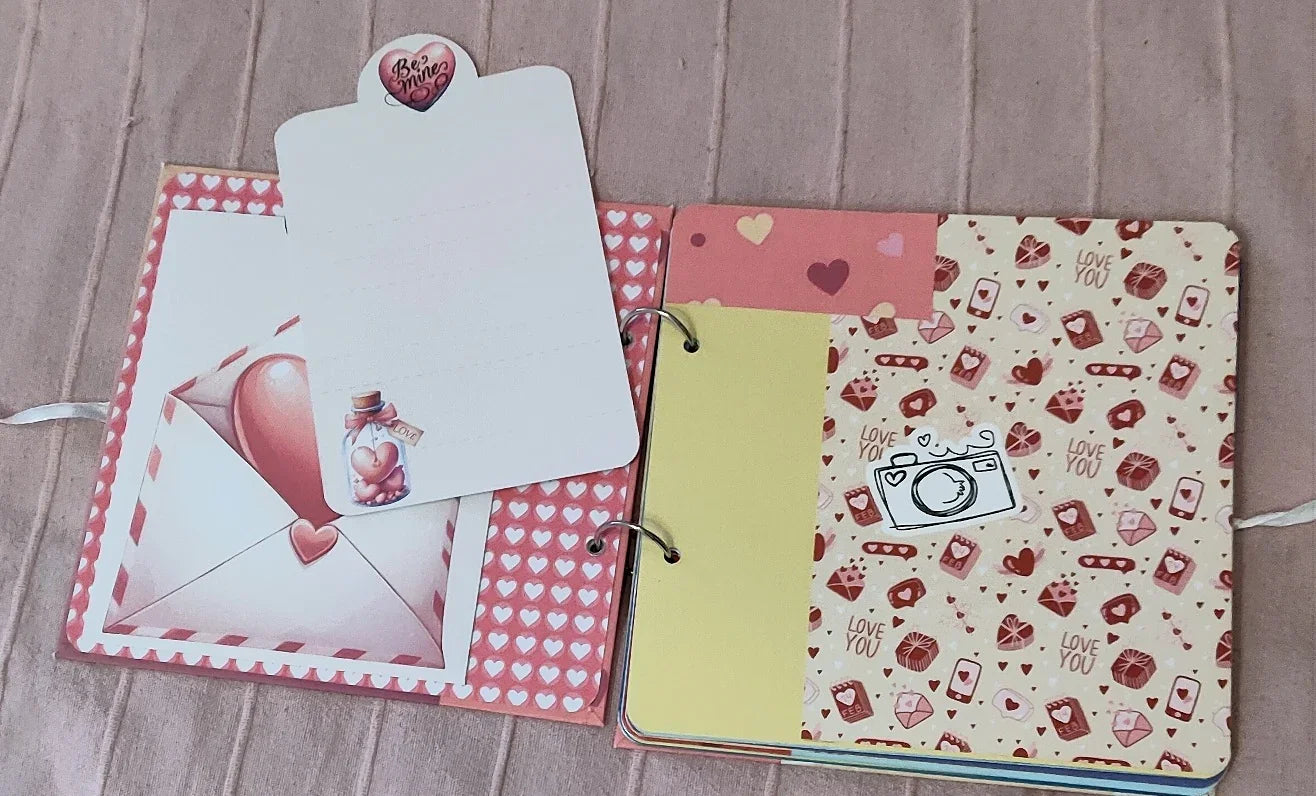 Handmade Valentine's scrapbook with heart, love, and camera decorations on a beige background