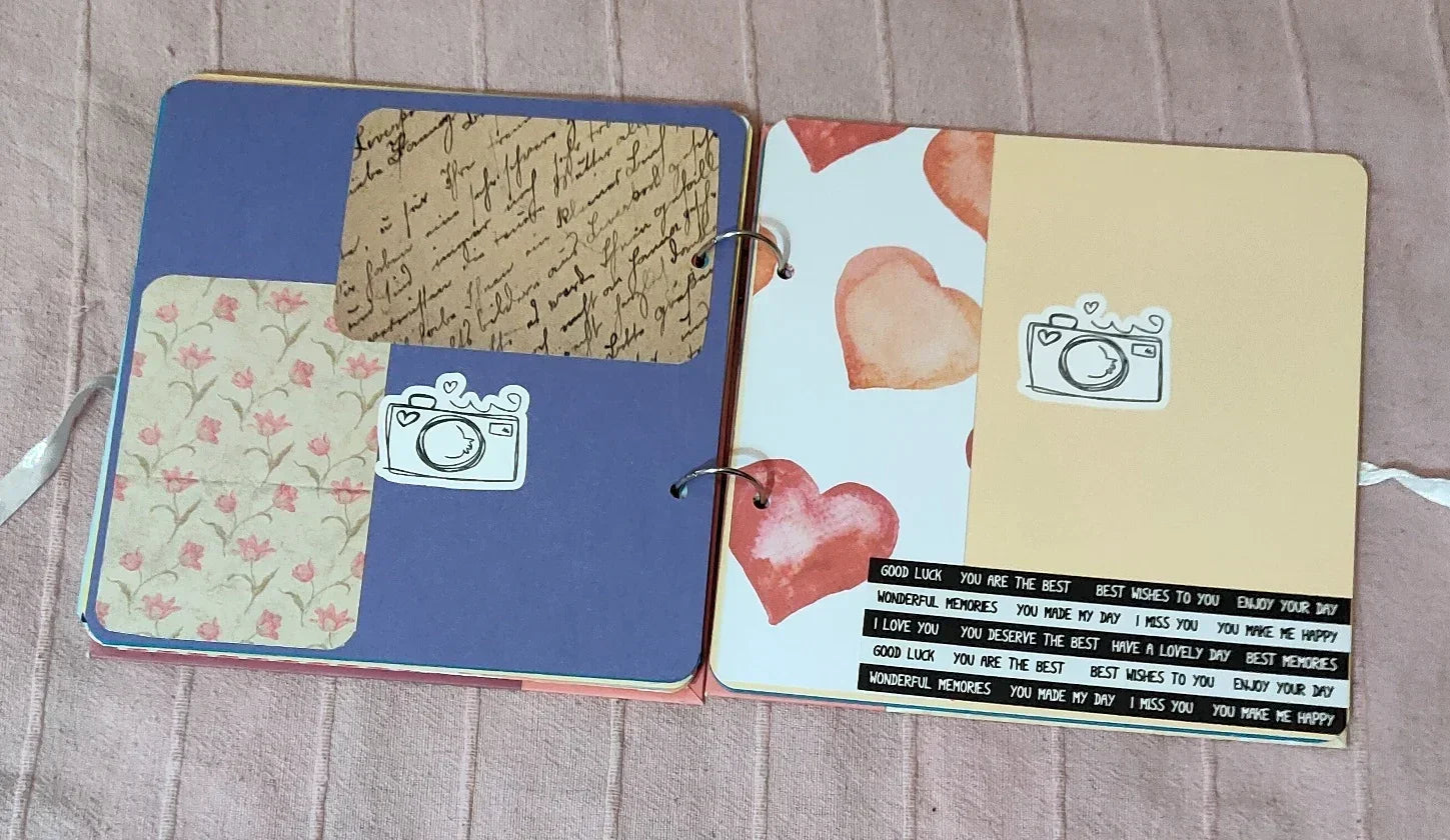 Handmade scrapbook with floral, heart patterns, camera stickers, and message strips on open pages