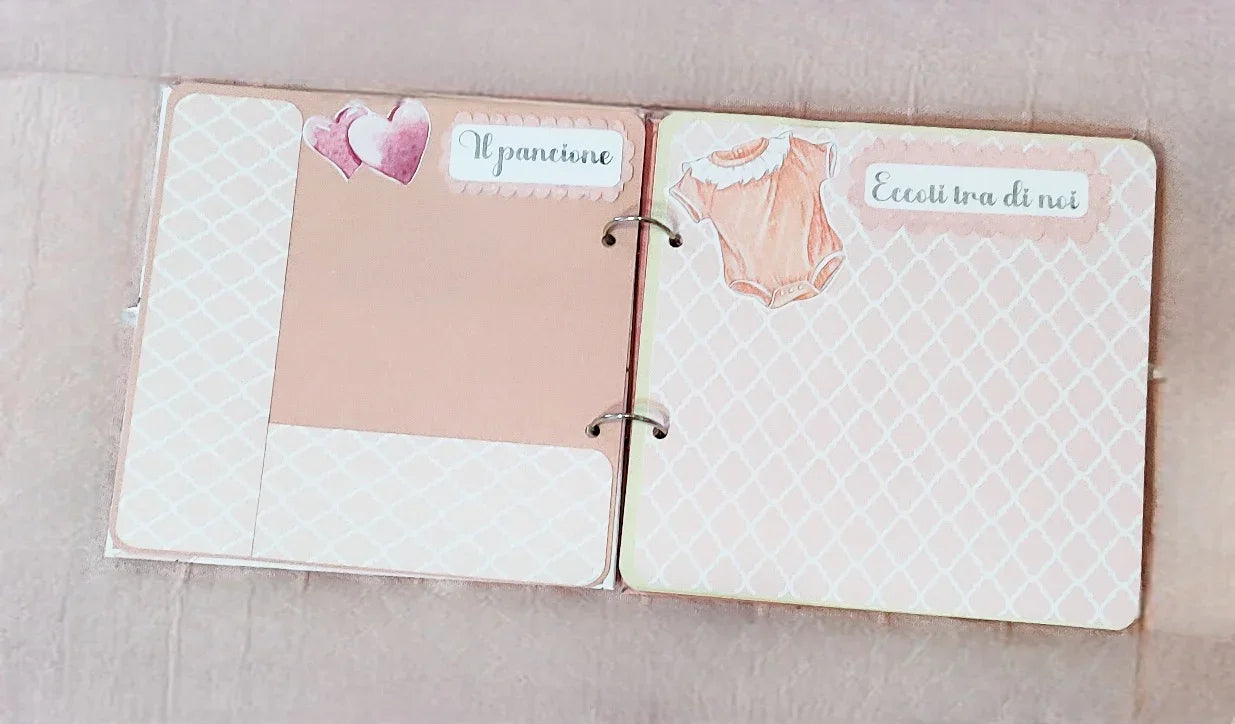 Pink baby girl scrapbook album pages with hearts and onesie illustration, Italian text.