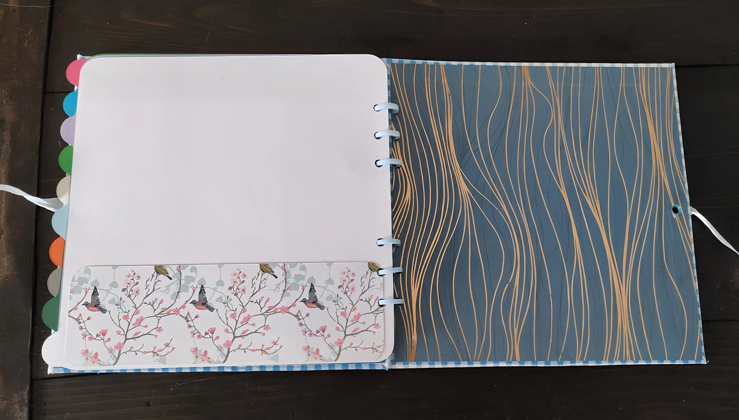 Open planner with pastel tab dividers, floral bird pocket, and blue wavy patterned cover