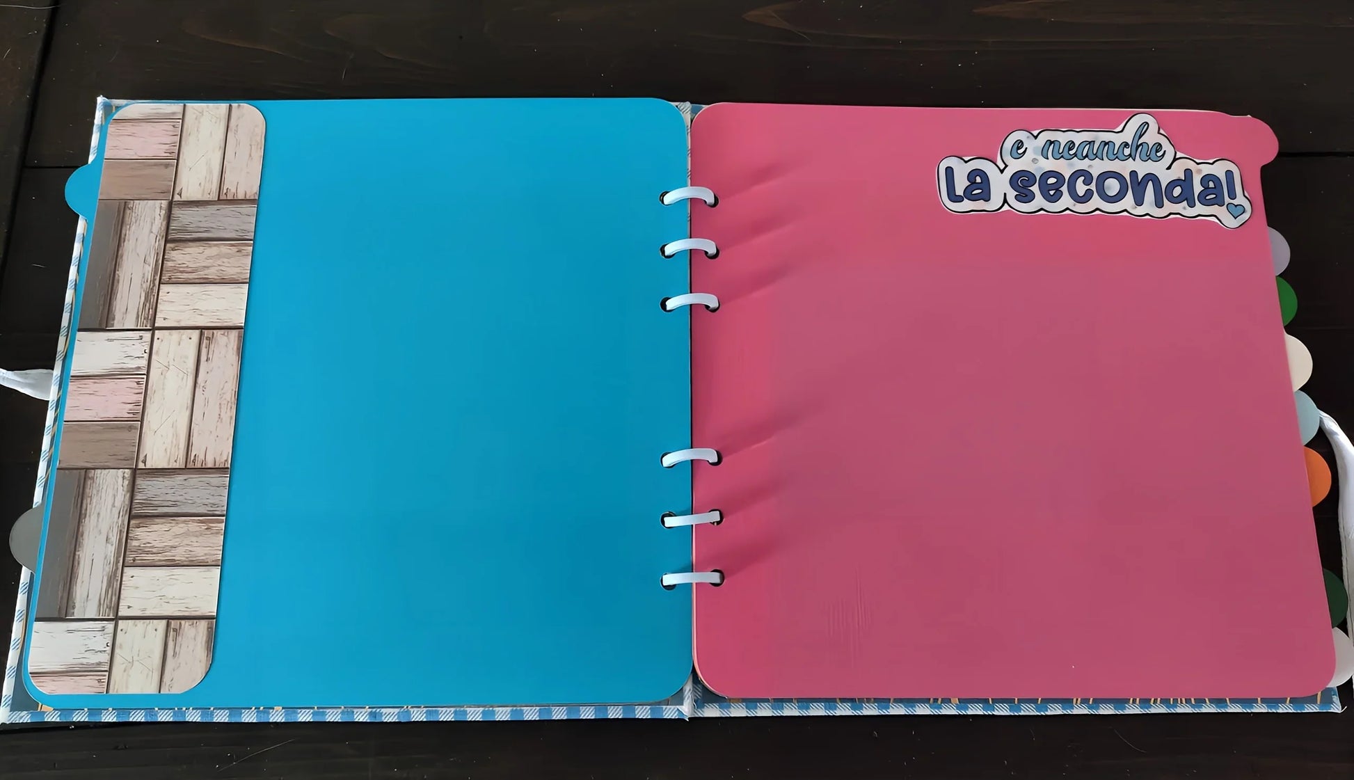 Open scrapbook with blue and pink pages, Italian sticker 'e neanche la seconda!'