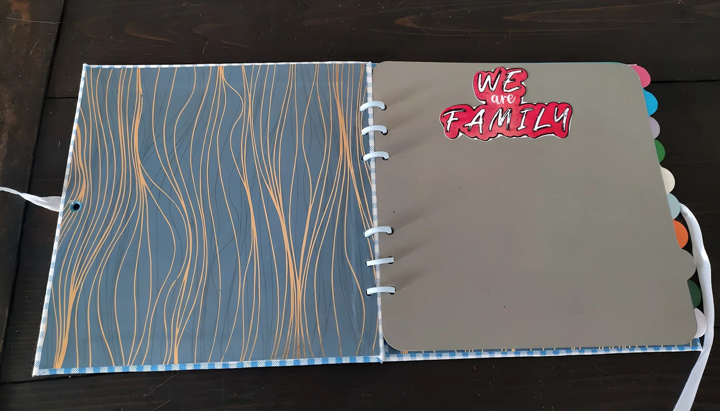 Open scrapbook with decorative cover, grey divider tab, and 'We Are Family' text sticker