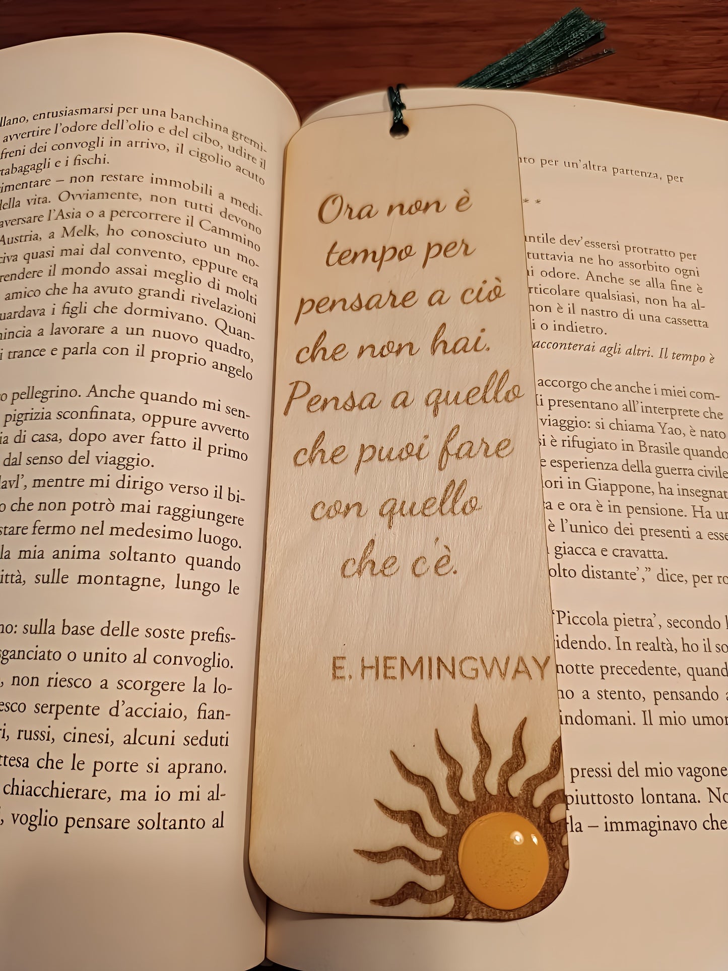 Wooden Hemingway quote bookmark with sun motif placed open on Italian book pages