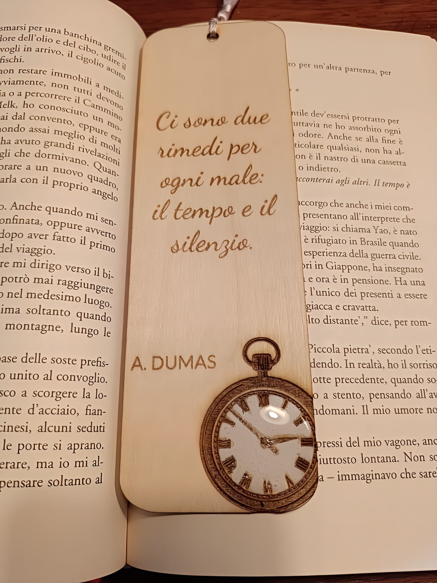 Wooden bookmark with Italian quote by A. Dumas and pocket watch, lying on an open book