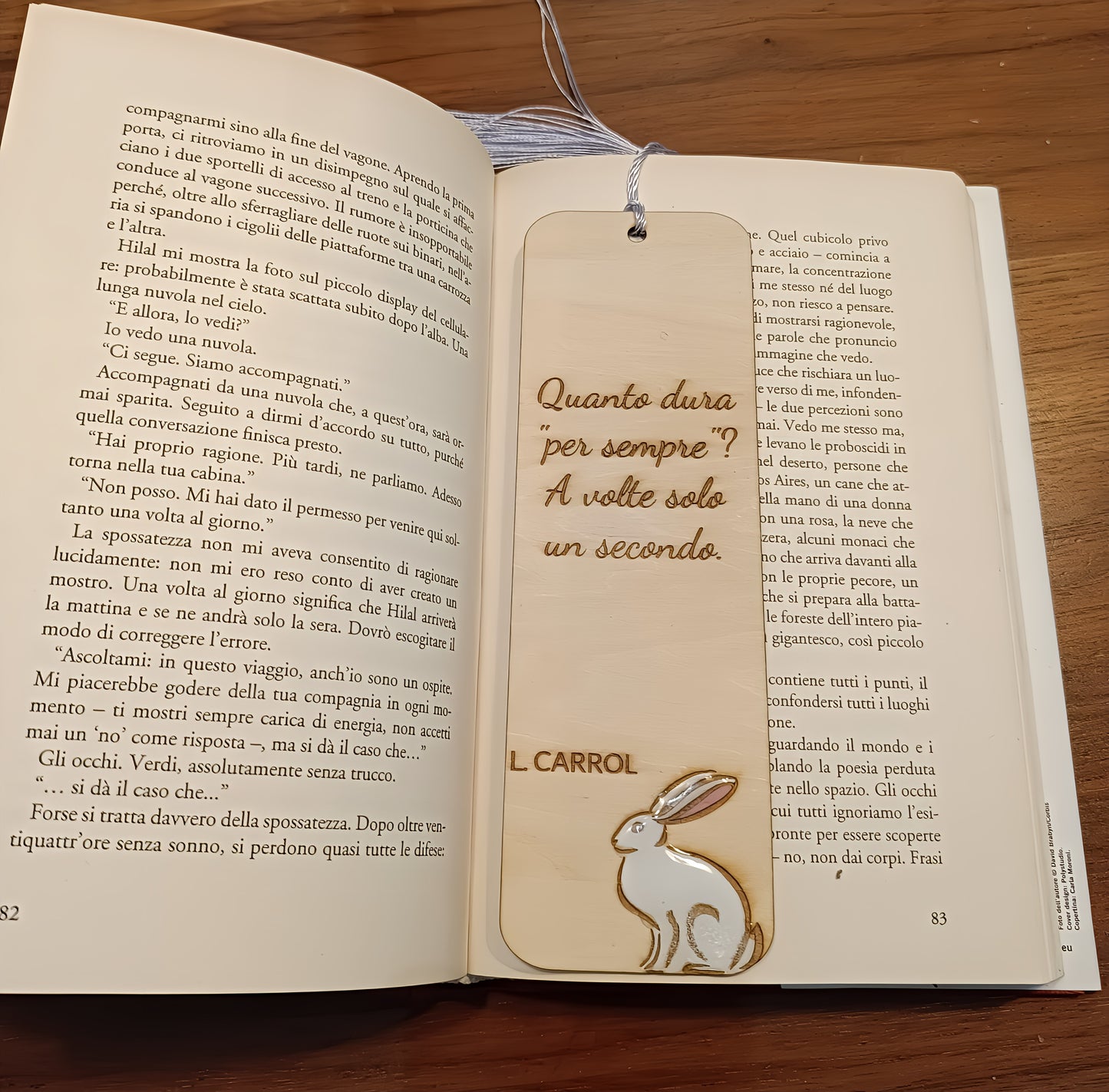 Wooden bookmark with rabbit illustration and Italian quote from Lewis Carroll in open book on table