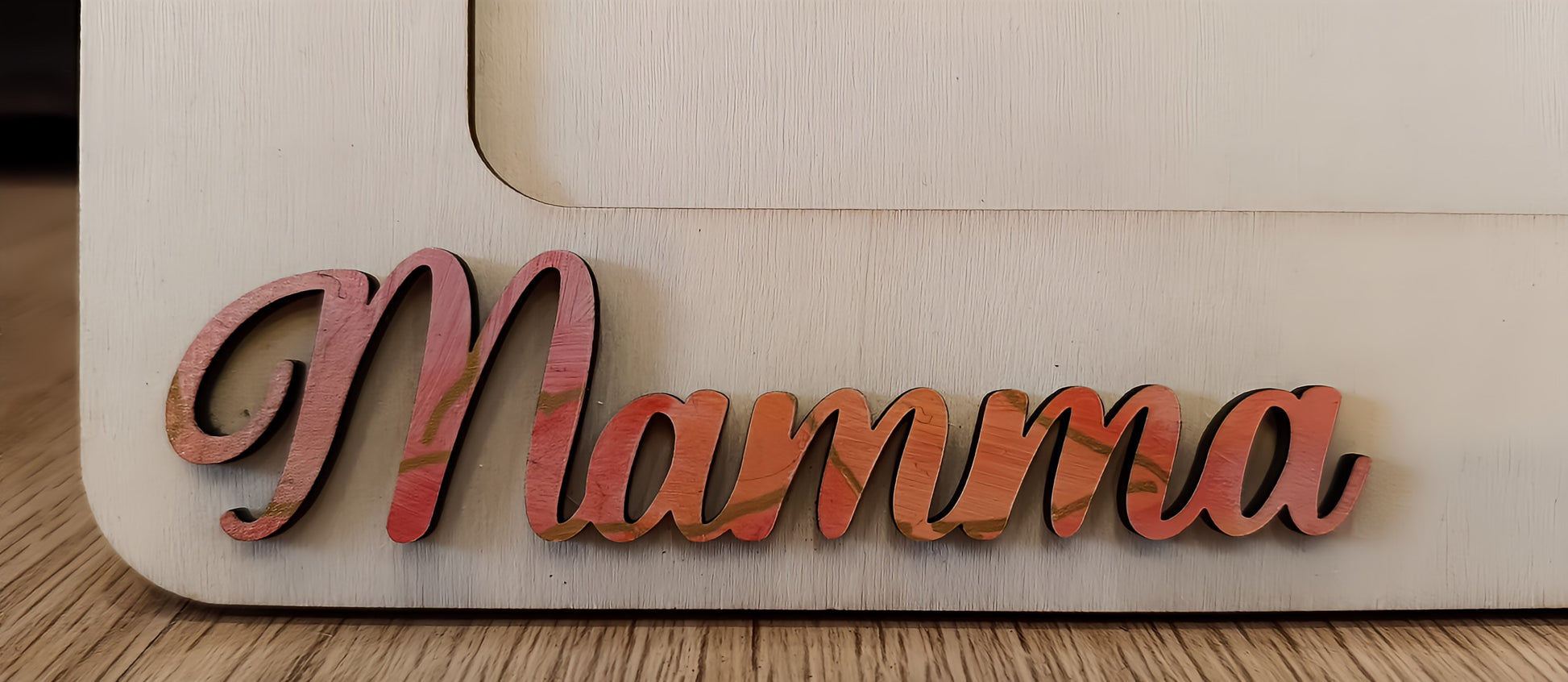Wooden cutout with 'Mamma' in pink script on a light wood background, Mother's Day decor