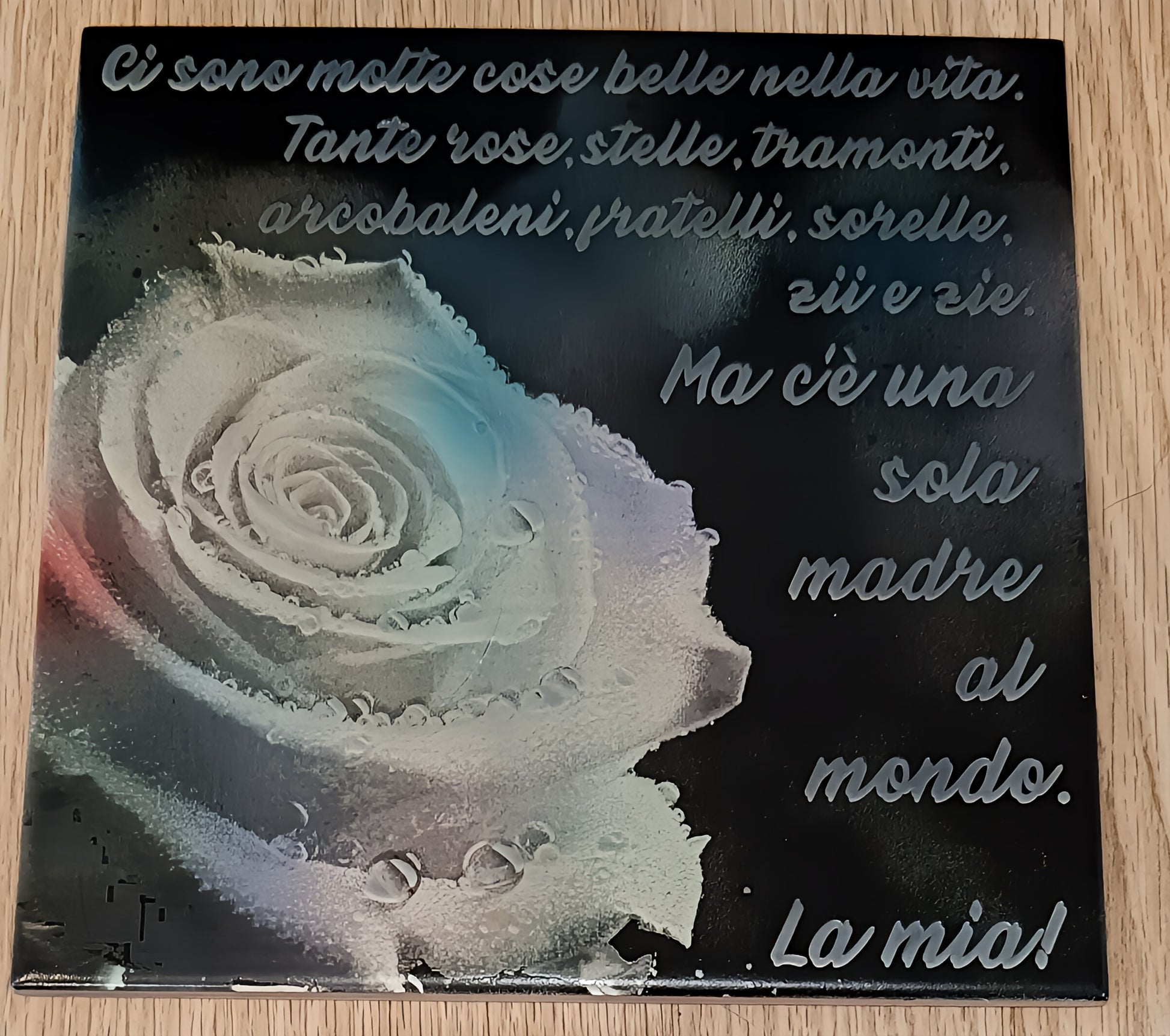 Decorative plaque with Italian text and a frosted white rose on a wooden surface