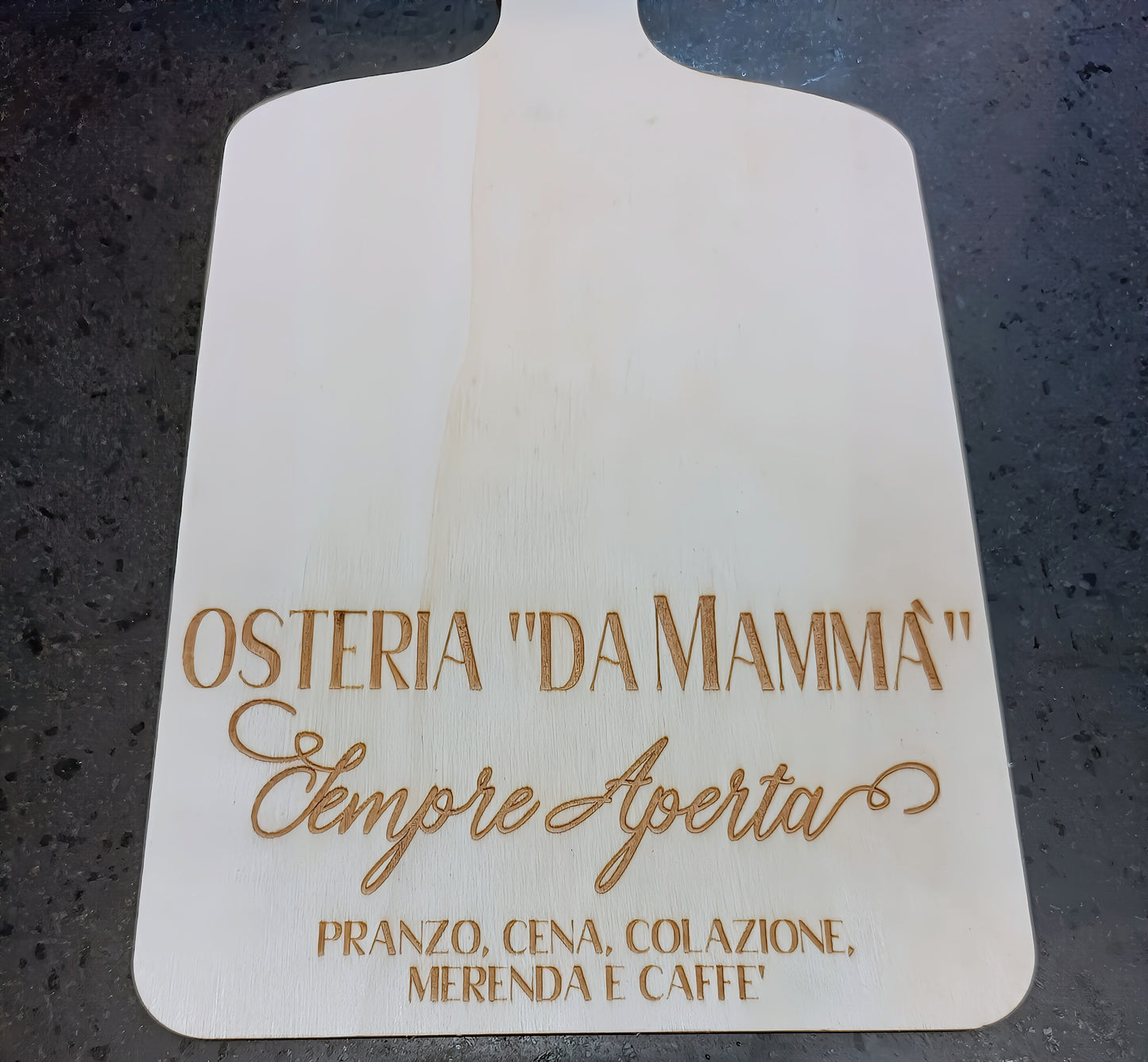 Osteria 'Da Mammà' engraved wooden pizza board on dark stone countertop