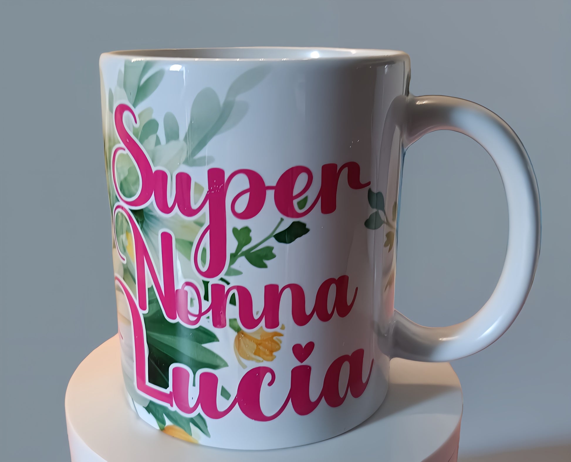 White ceramic mug with pink text 'Super Nonna Lucia' and green floral design