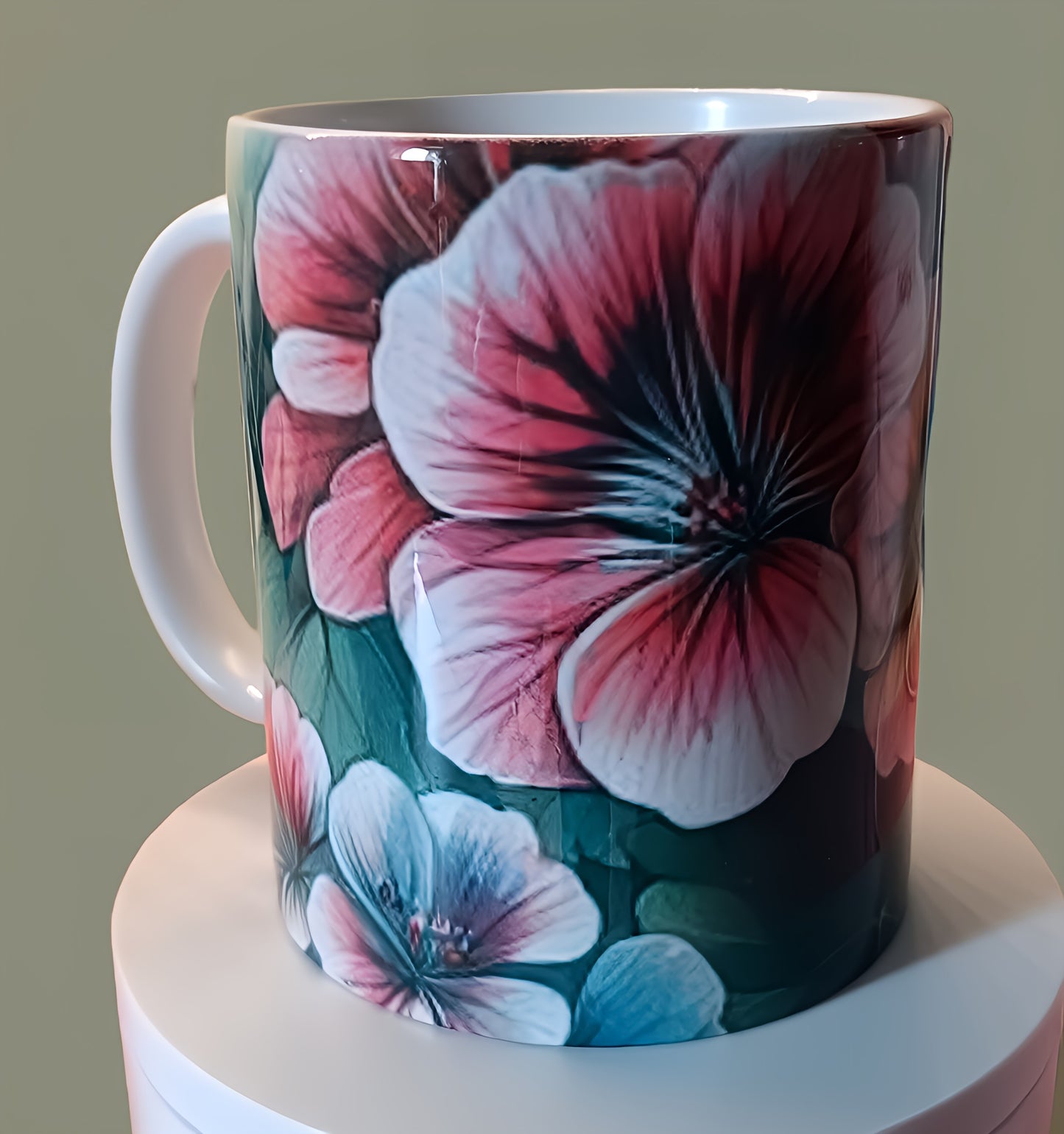 Ceramic mug with pink and blue floral design on display against neutral background