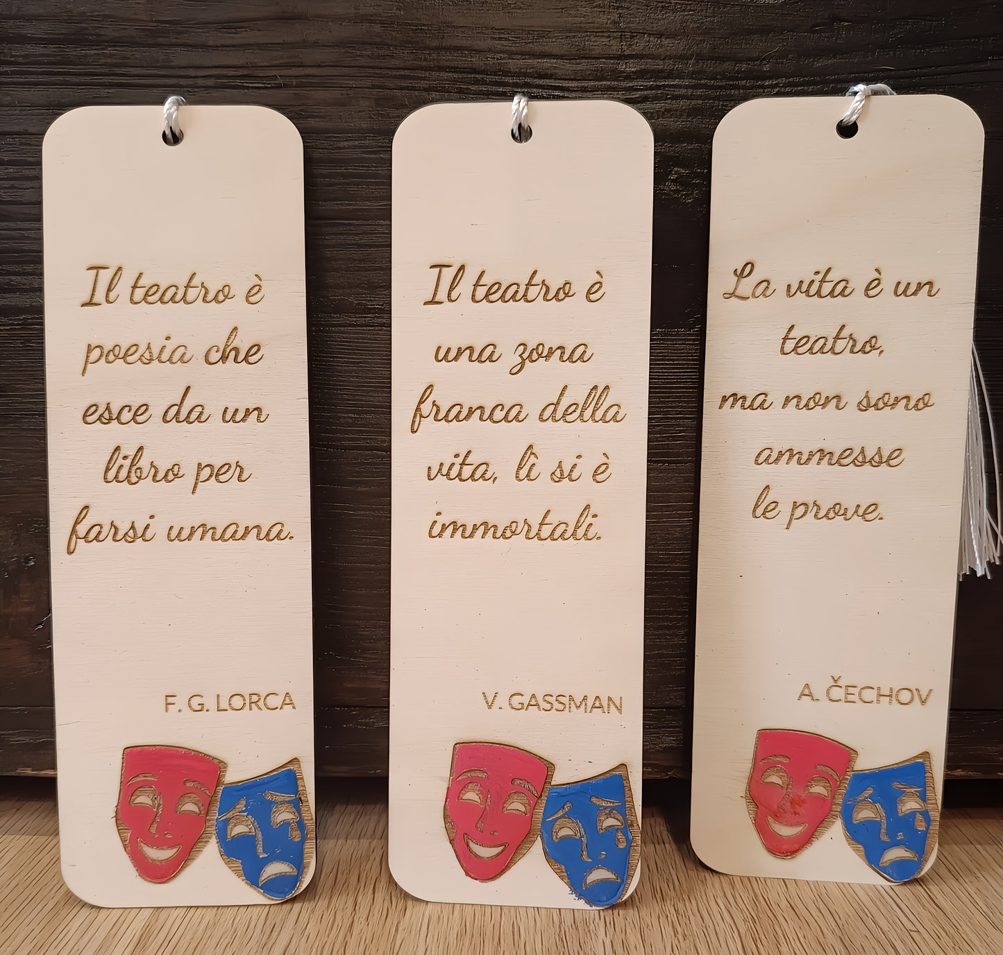 Three wooden bookmarks with Italian theatre quotes, engraved text, and comedy-tragedy masks.
