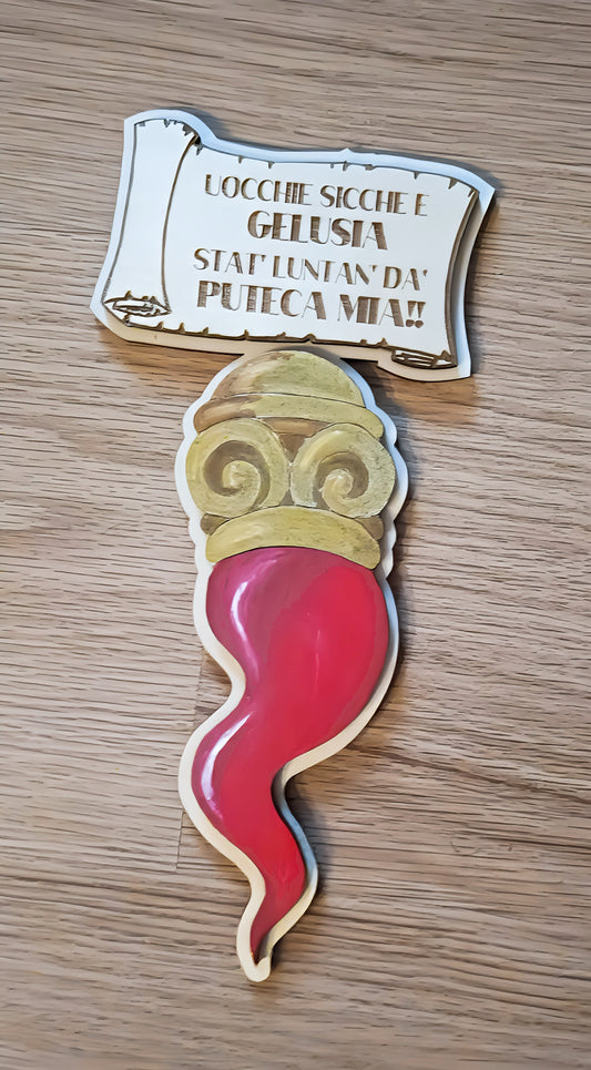 Wooden Italian cornicello charm with engraved message on light wood surface