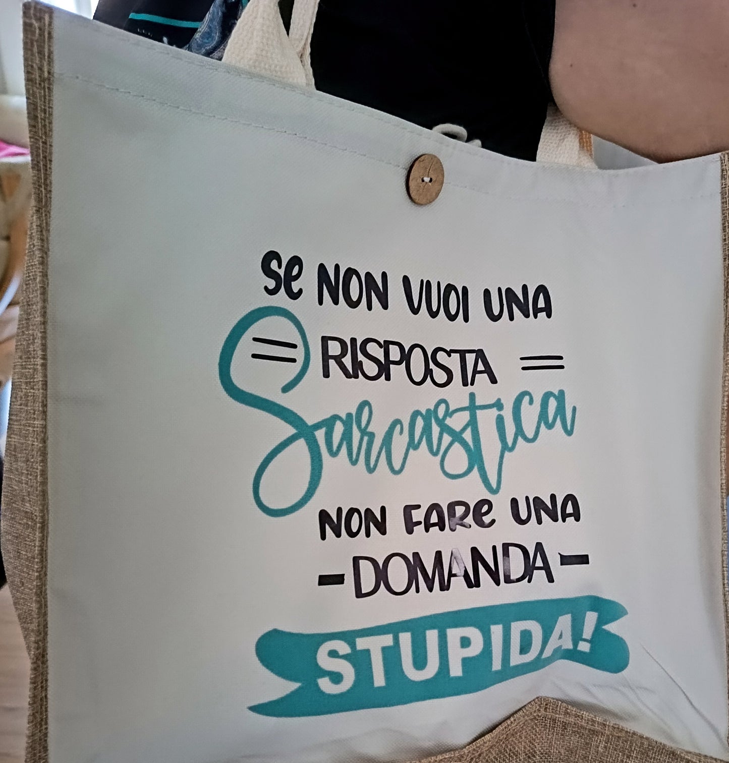 Tote bag with Italian sarcastic quote, beige handles, button detail, and bold text design
