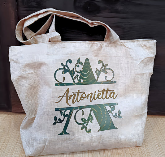 Beige tote bag with decorative green letter A and Antonietta text on wooden floor