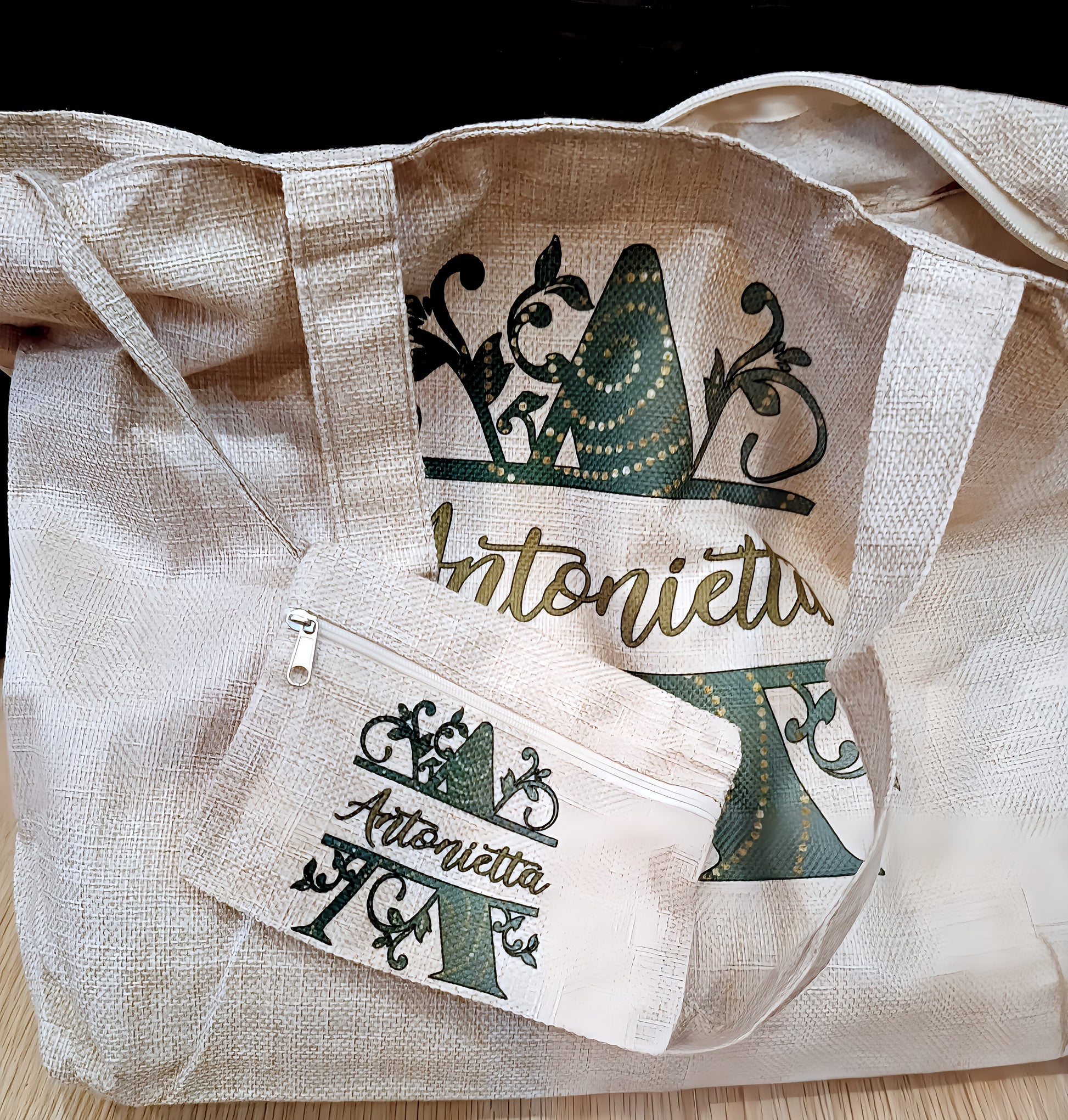 Beige textured tote bag and pouch with green Antonietta logo on a wood surface