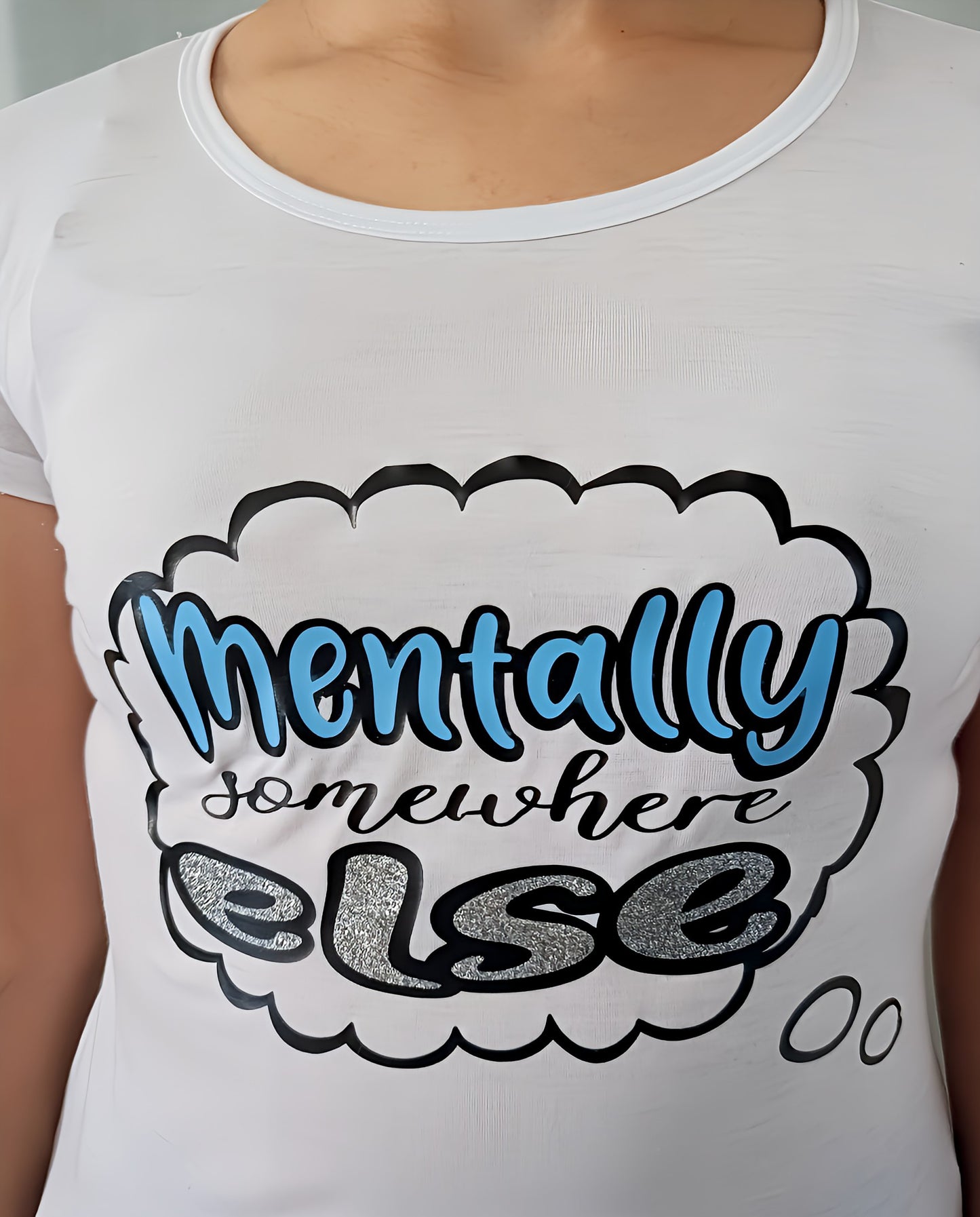 White t-shirt with 'Mentally somewhere else' text bubble graphic in blue and silver glitter.