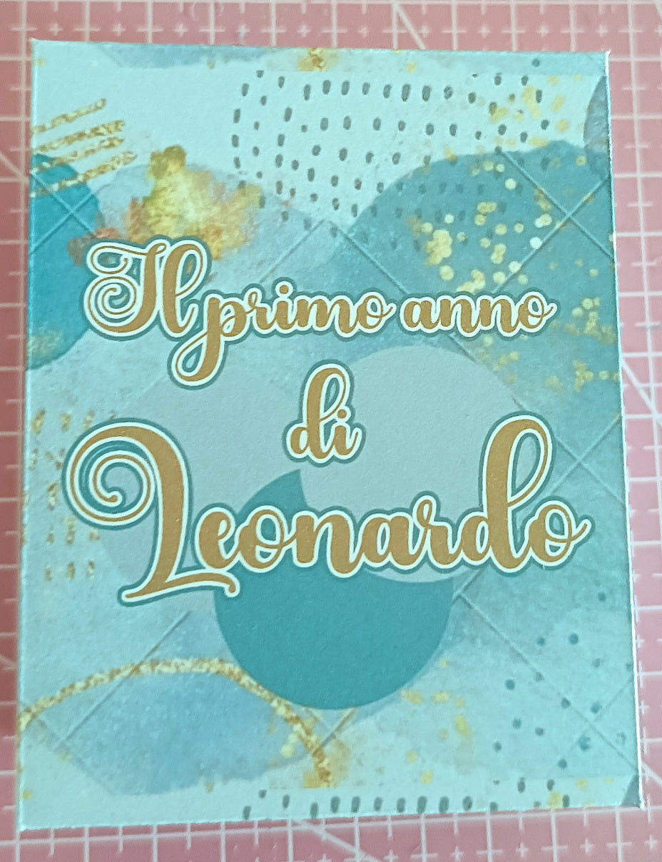 Blue and gold scrapbook cover with Italian text 'Il primo anno di Leonardo' on patterned background