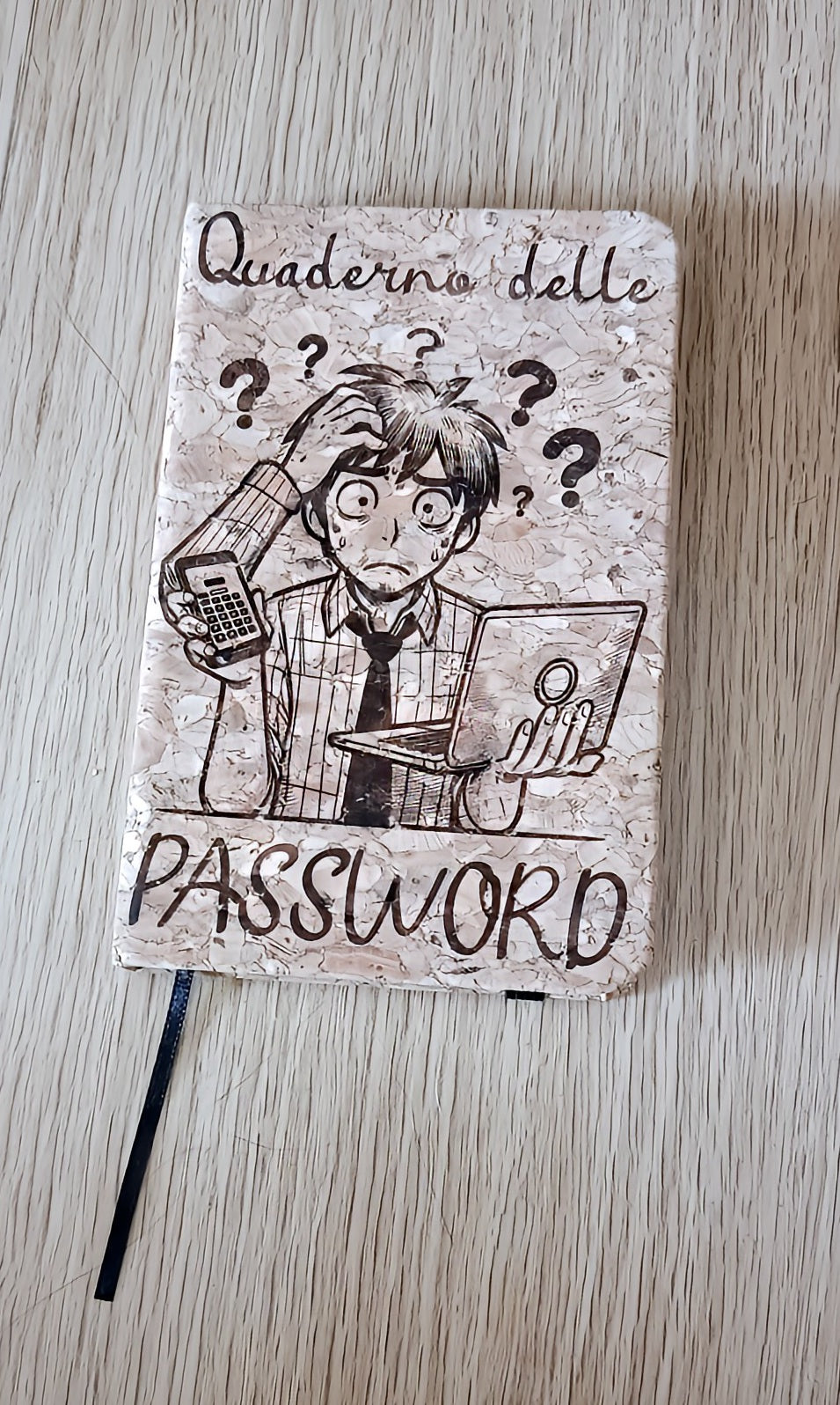Password notebook with cartoon man confused, holding calculator and laptop on wood table