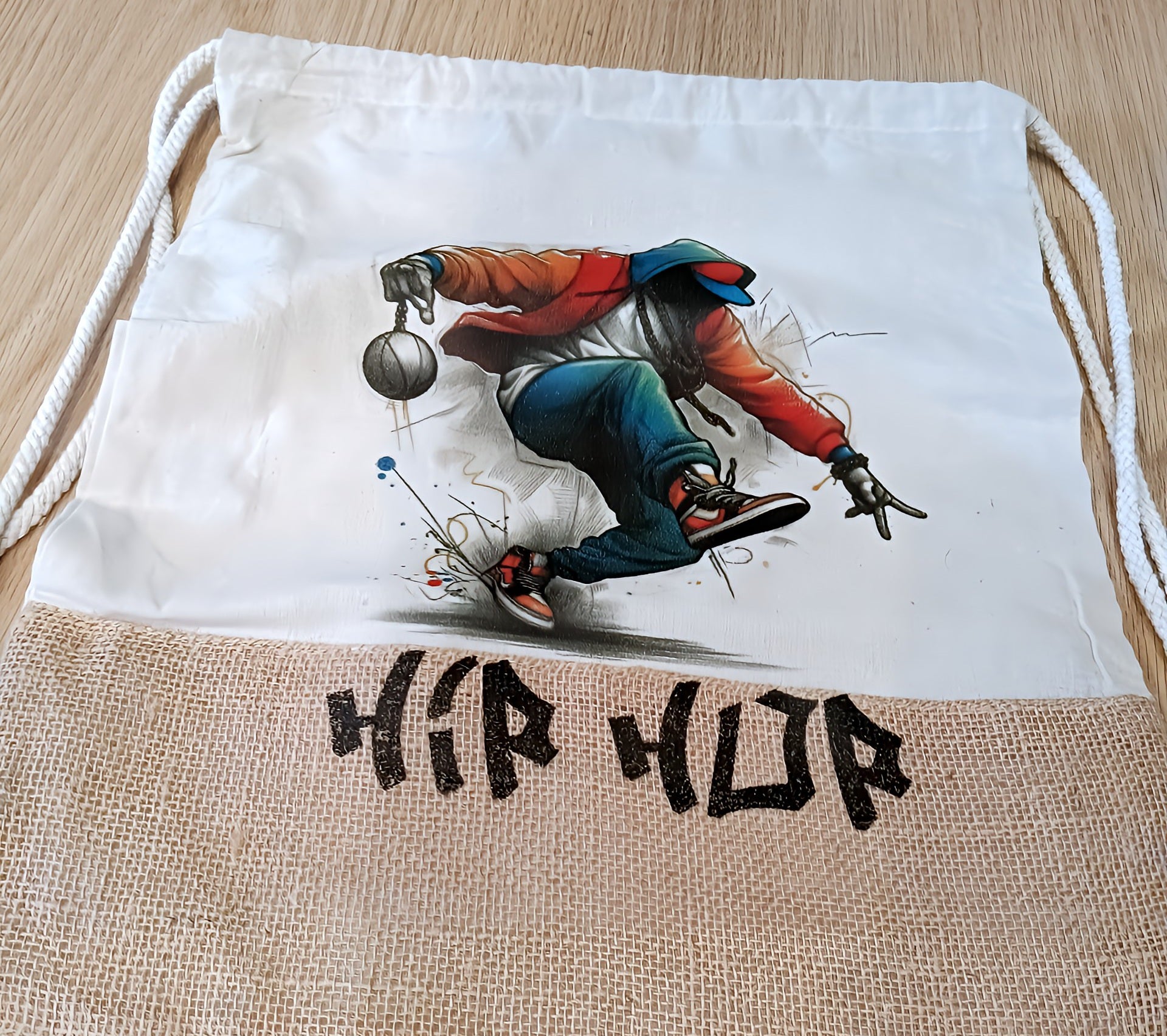 Hip hop drawstring bag featuring breakdancer illustration on white and burlap fabric