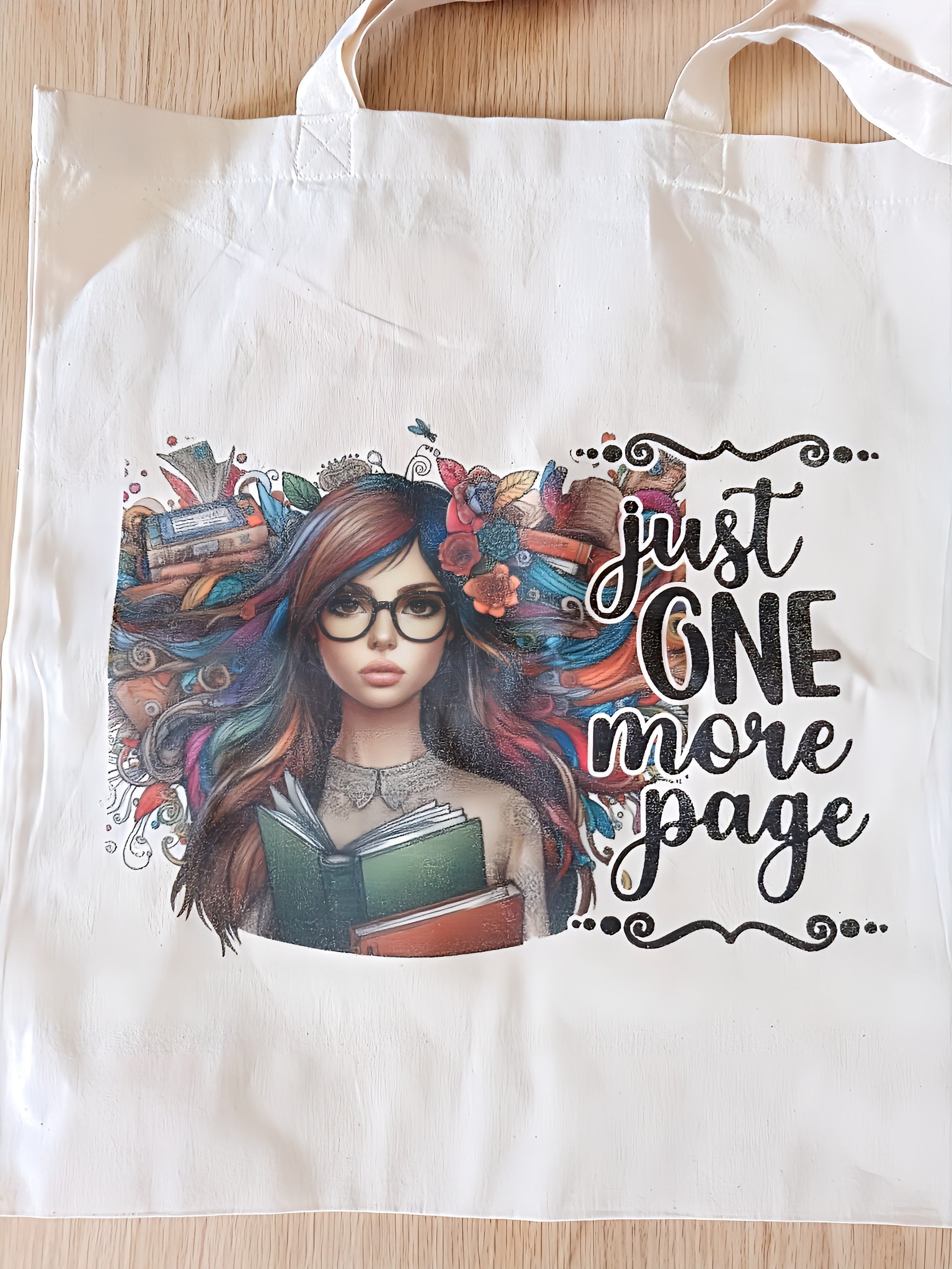 Tote bag with a colorful illustration of a woman holding books and text 'just one more page'.