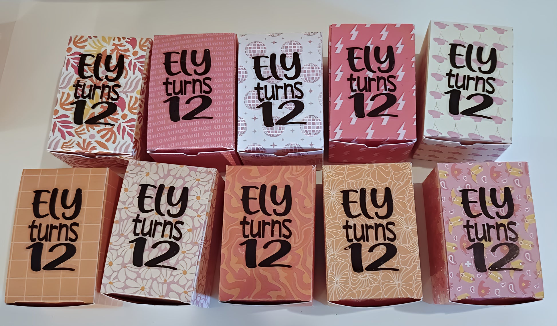 Assorted colorful birthday boxes with 'Ely turns 12' printed, perfect party favors