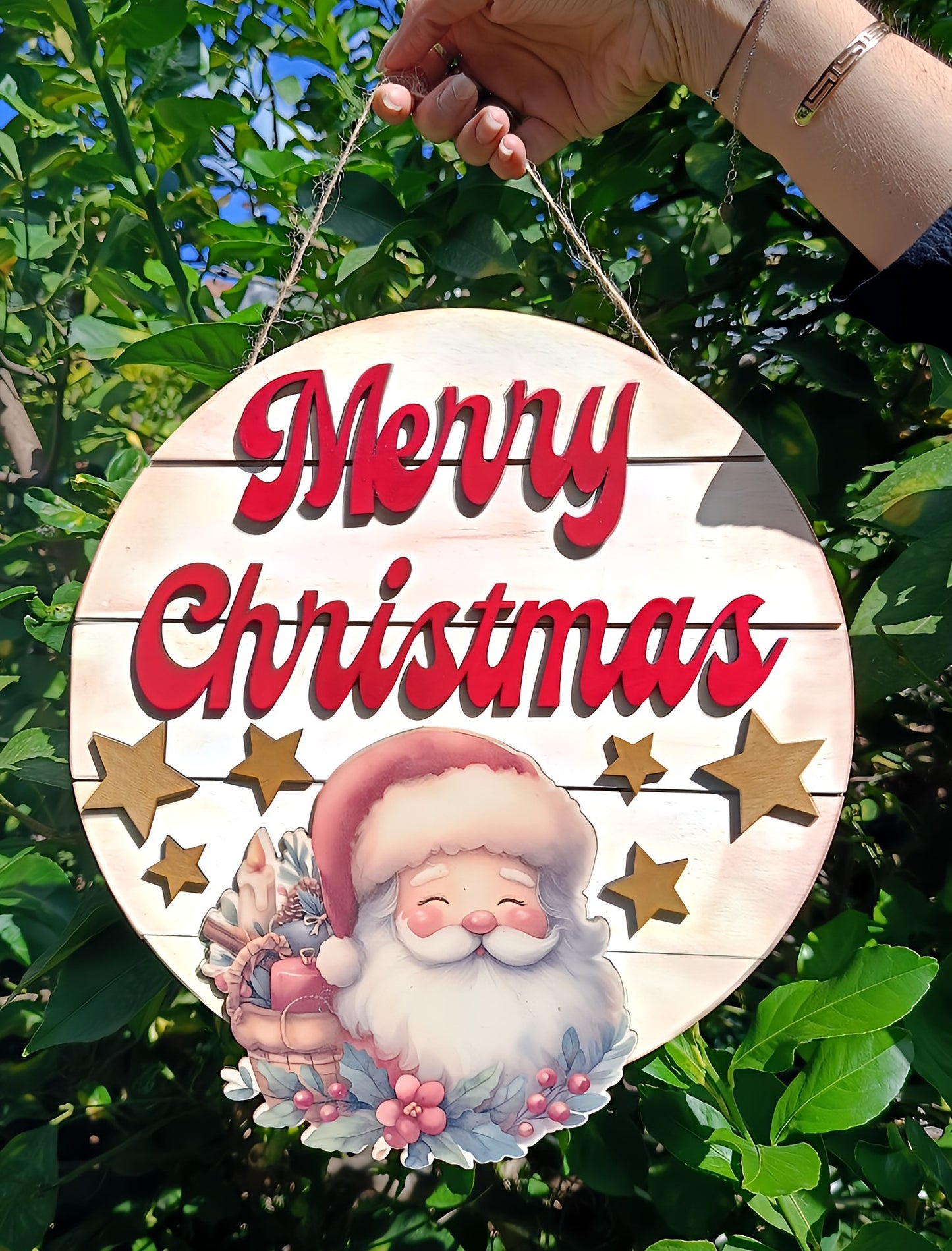 Hand holding Merry Christmas sign with Santa and stars, outdoor holiday decoration