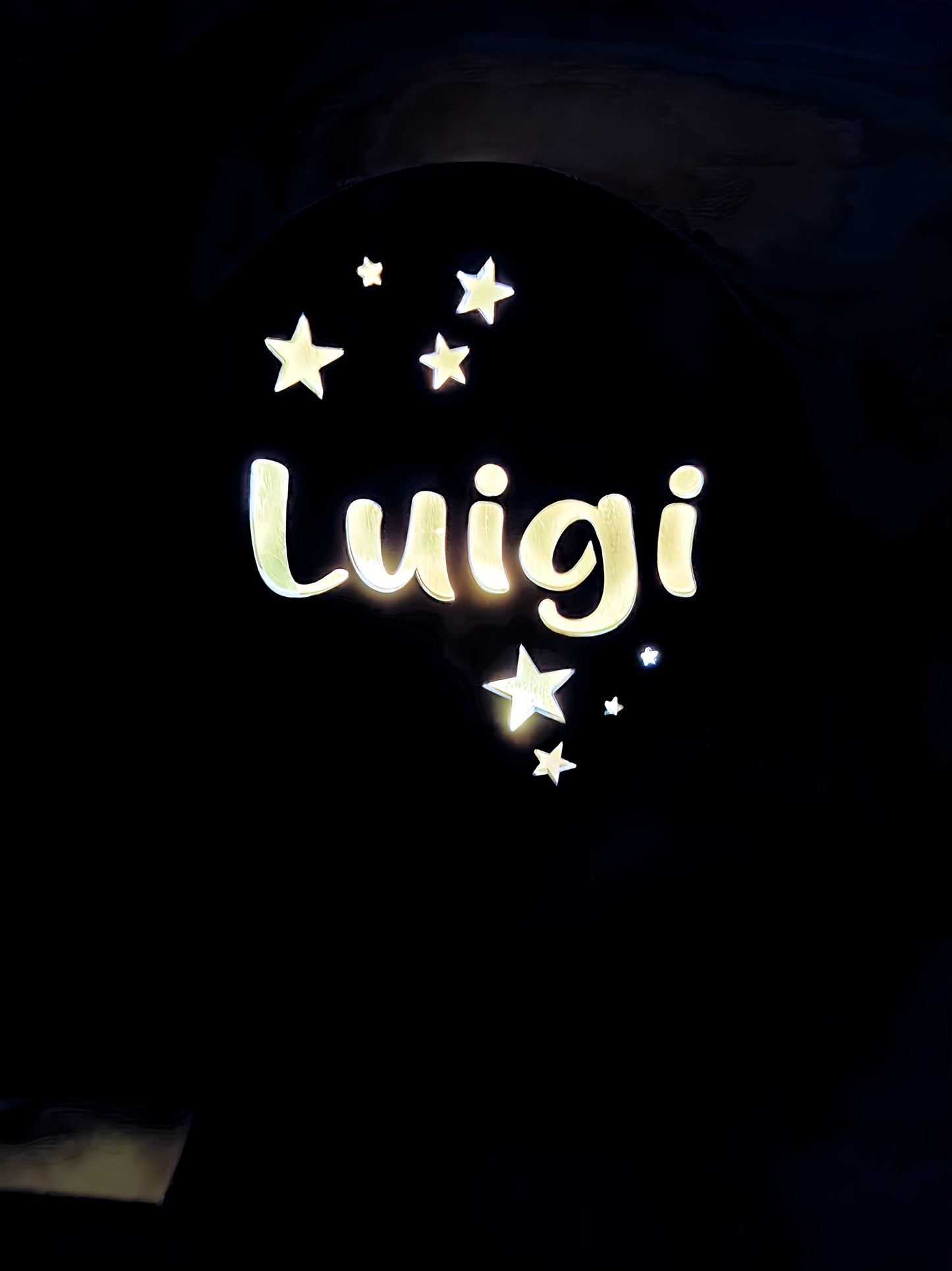 Illuminated Luigi name sign with glowing stars on a dark background