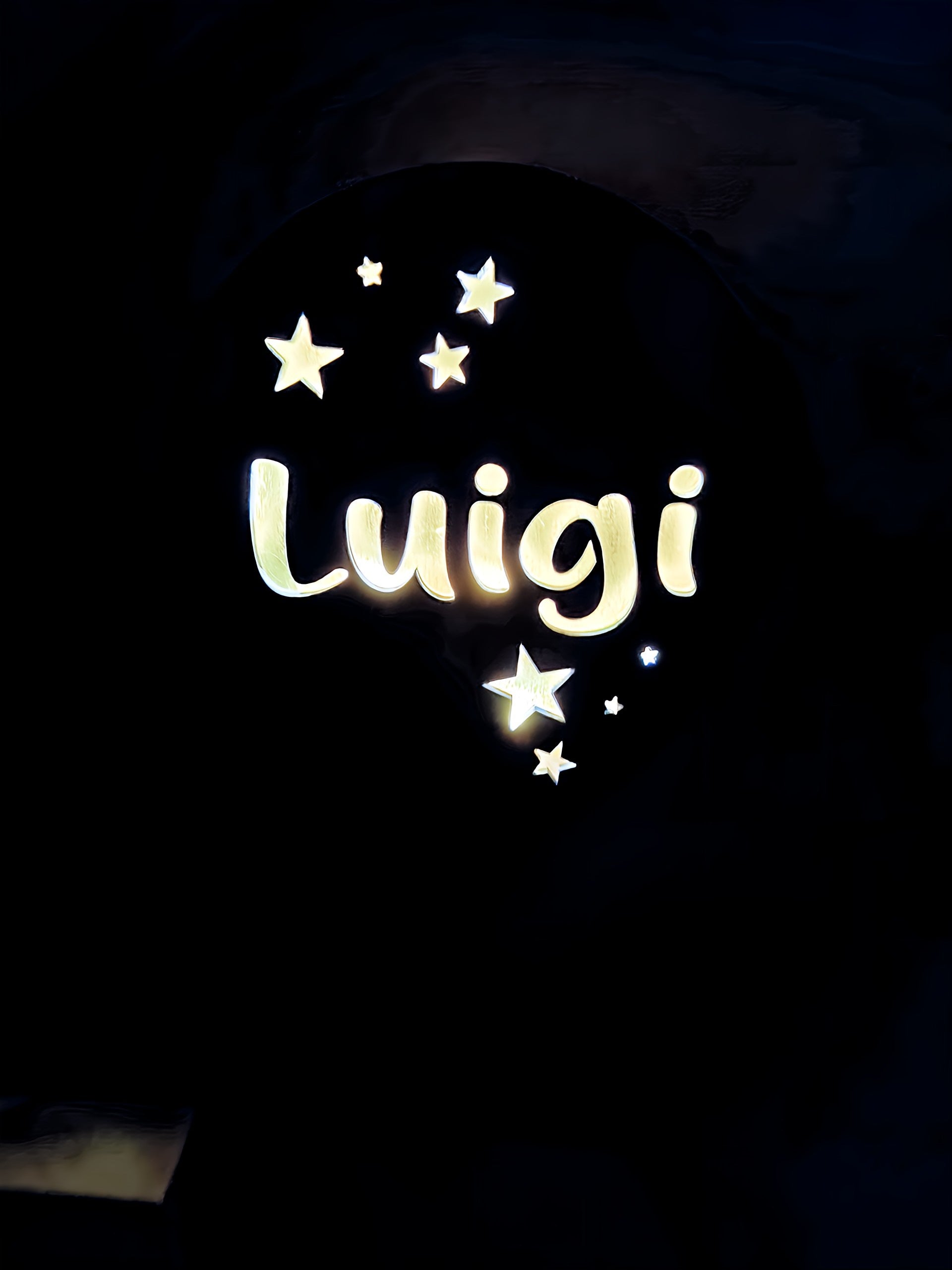 Illuminated Luigi name sign with glowing stars on a dark background
