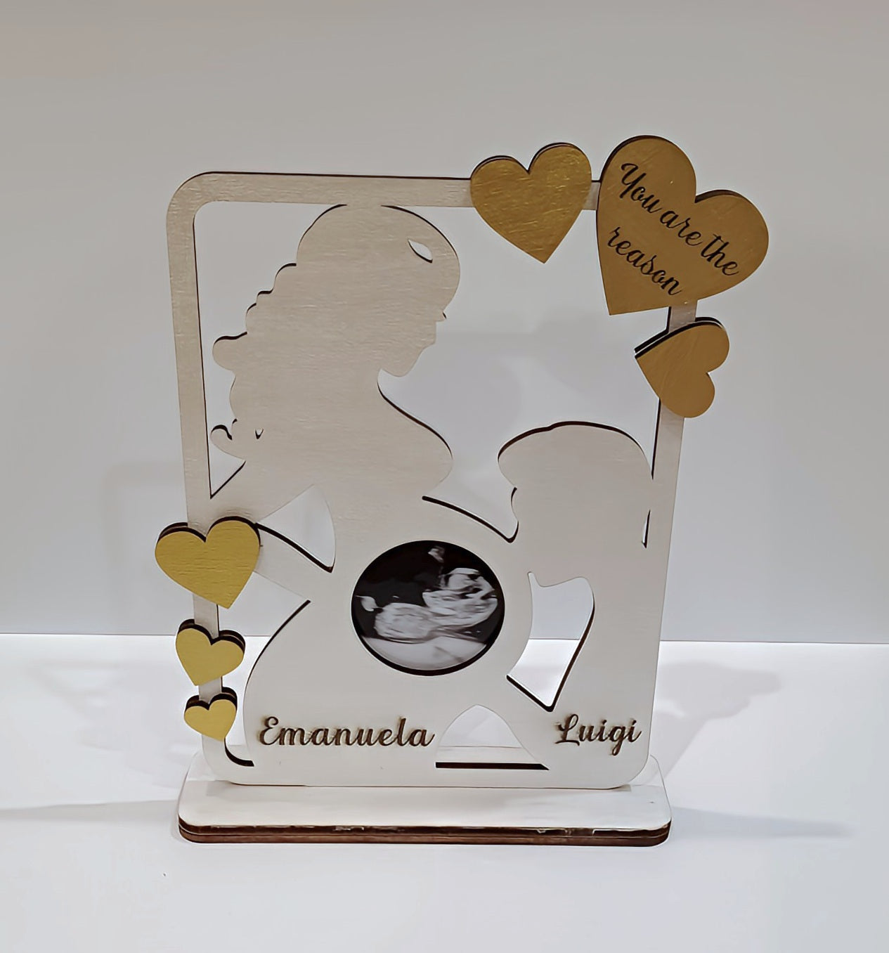 Personalized wooden pregnancy photo frame with hearts and silhouette, names Emanuela Luigi, ultrasound photo, 'You are the reason' message.