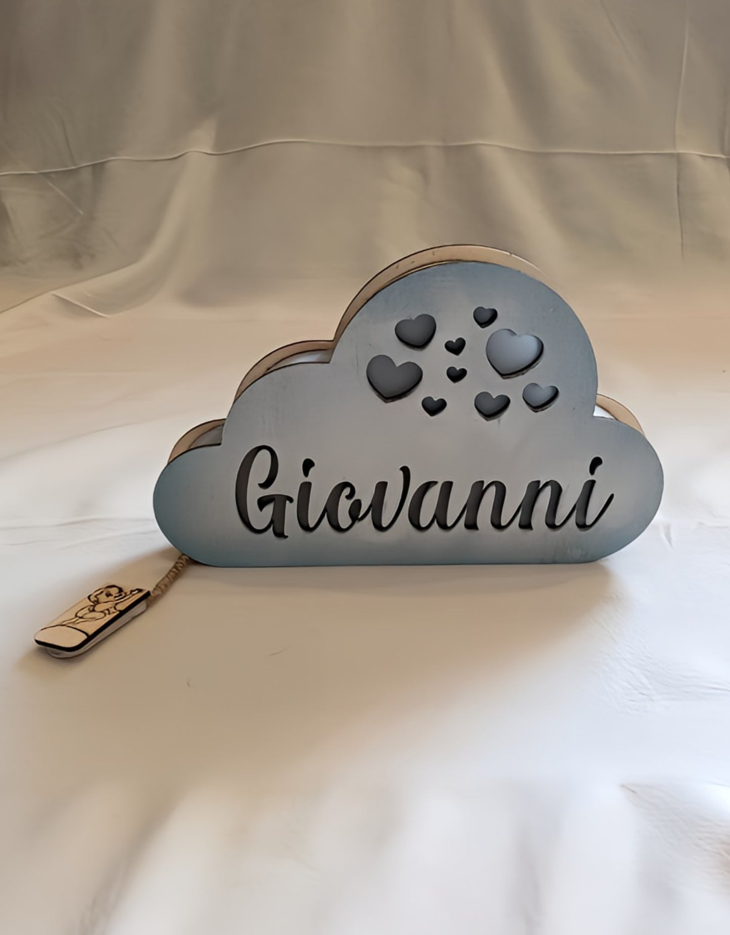 Personalized cloud-shaped wooden name sign with hearts and the name Giovanni, on white fabric.