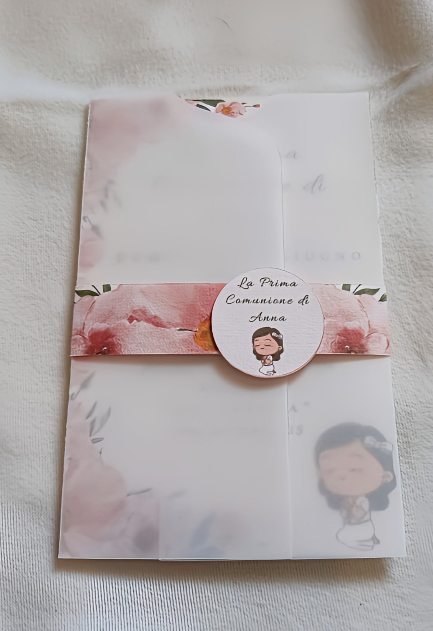First Communion invitation with floral design and cartoon girl on white fabric background