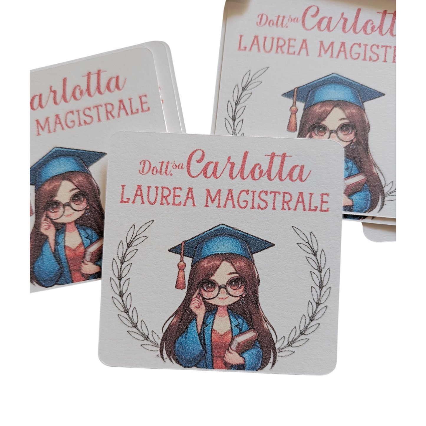Graduation card with cartoon girl in cap and gown, holding book, Laurea Magistrale text.