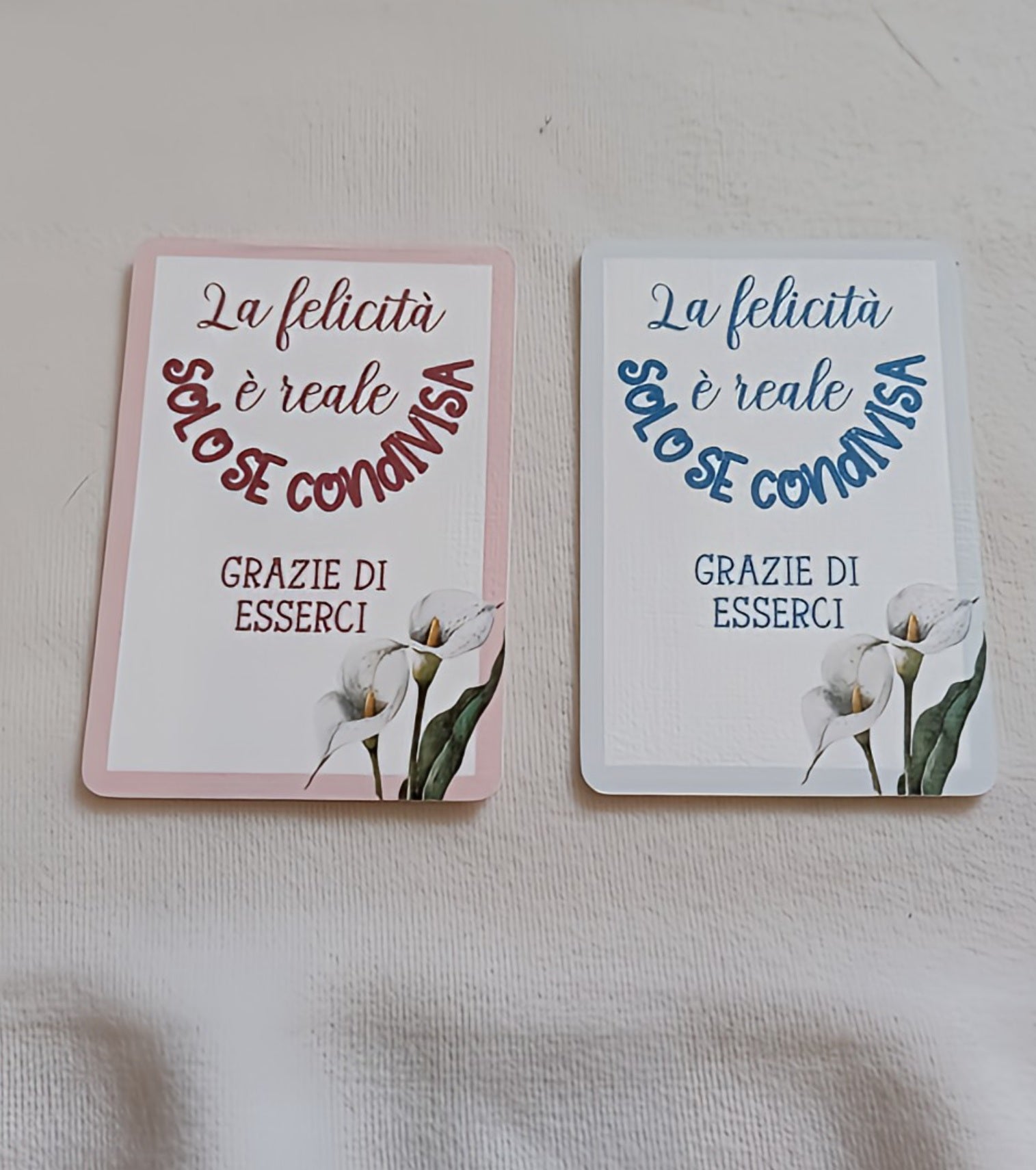 Two Italian greeting cards with calla lilies and inspirational text on a pale fabric background