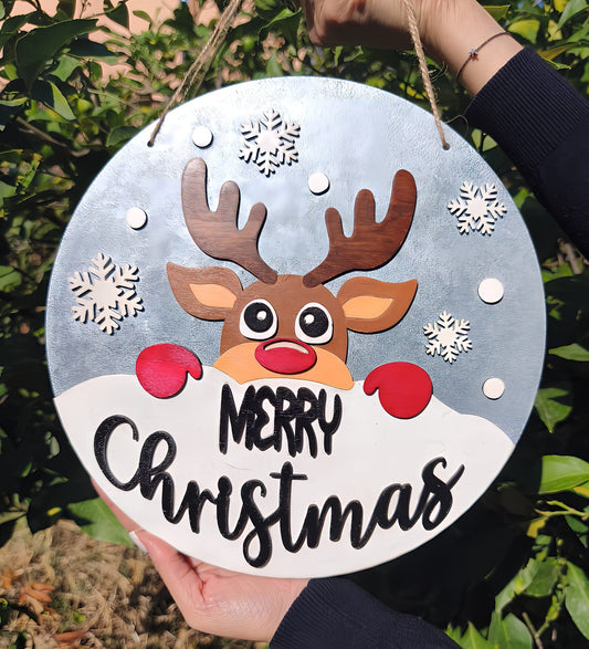 Hand holding round Merry Christmas sign with reindeer, snowflakes, and festive design