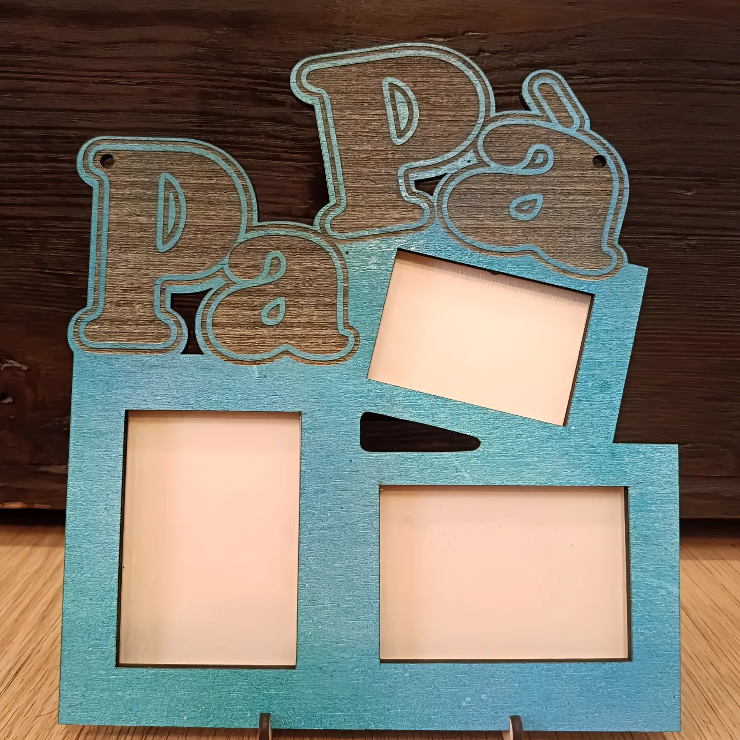 Blue wooden 'Papá' photo frame with three empty picture slots, on wood background.